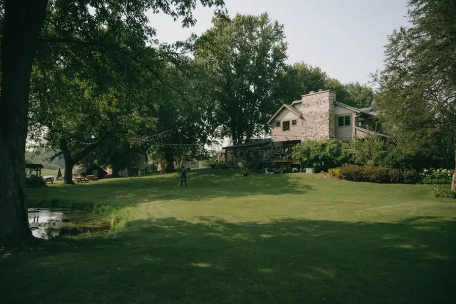 A cleared, raked lawn under mature trees beside a house